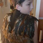 A girl wearing a steampunk costume showcasing feathers at Carlie's Art Gallery.