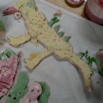 Carlie's Art Gallery: A child is sculpting a clay dinosaur on a table.