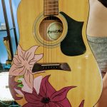 An acoustic guitar transformed into an artistic masterpiece with flowers by Carlie's Art Gallery.