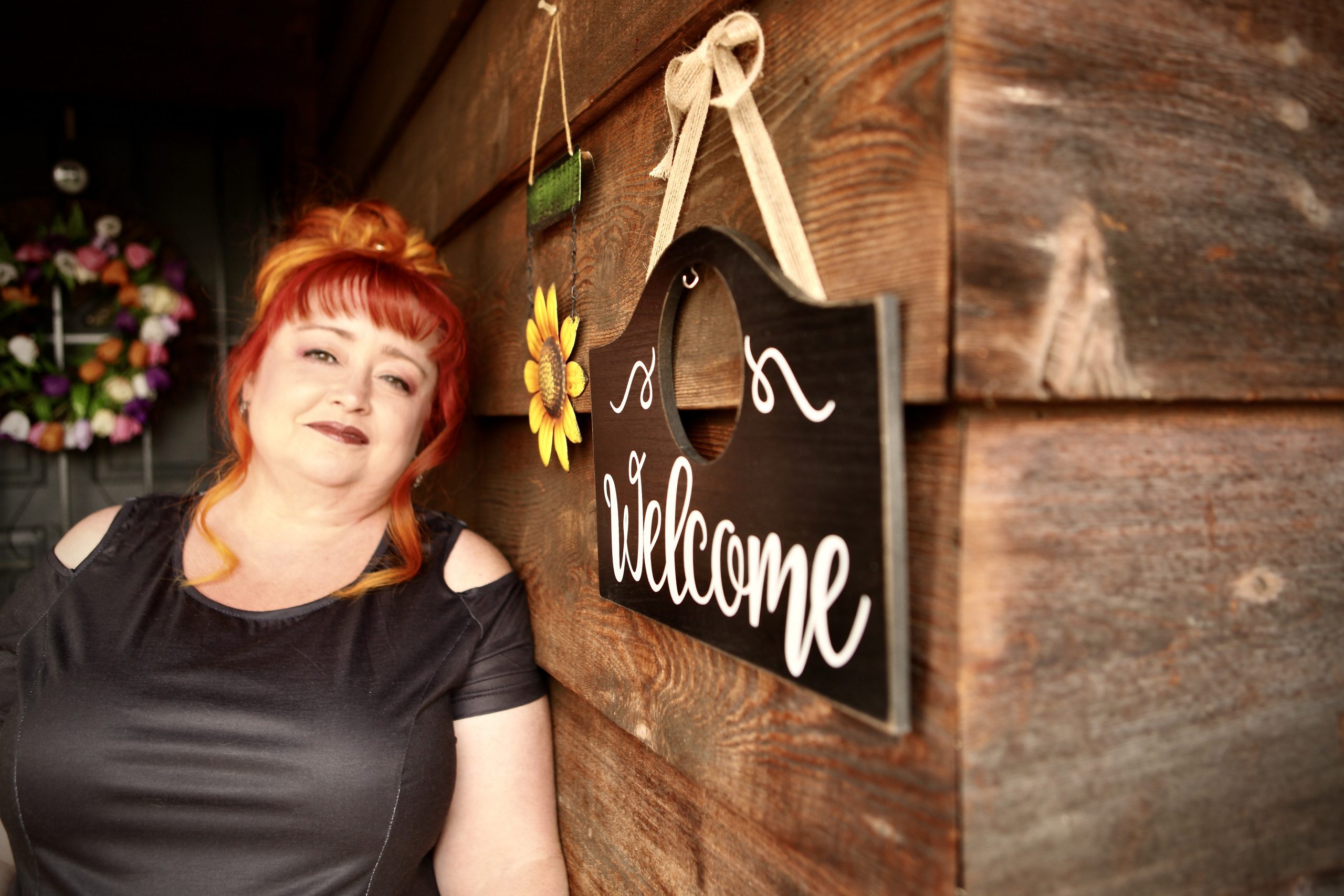 Michelle Bell on wooden wall background and welcome sign on the right