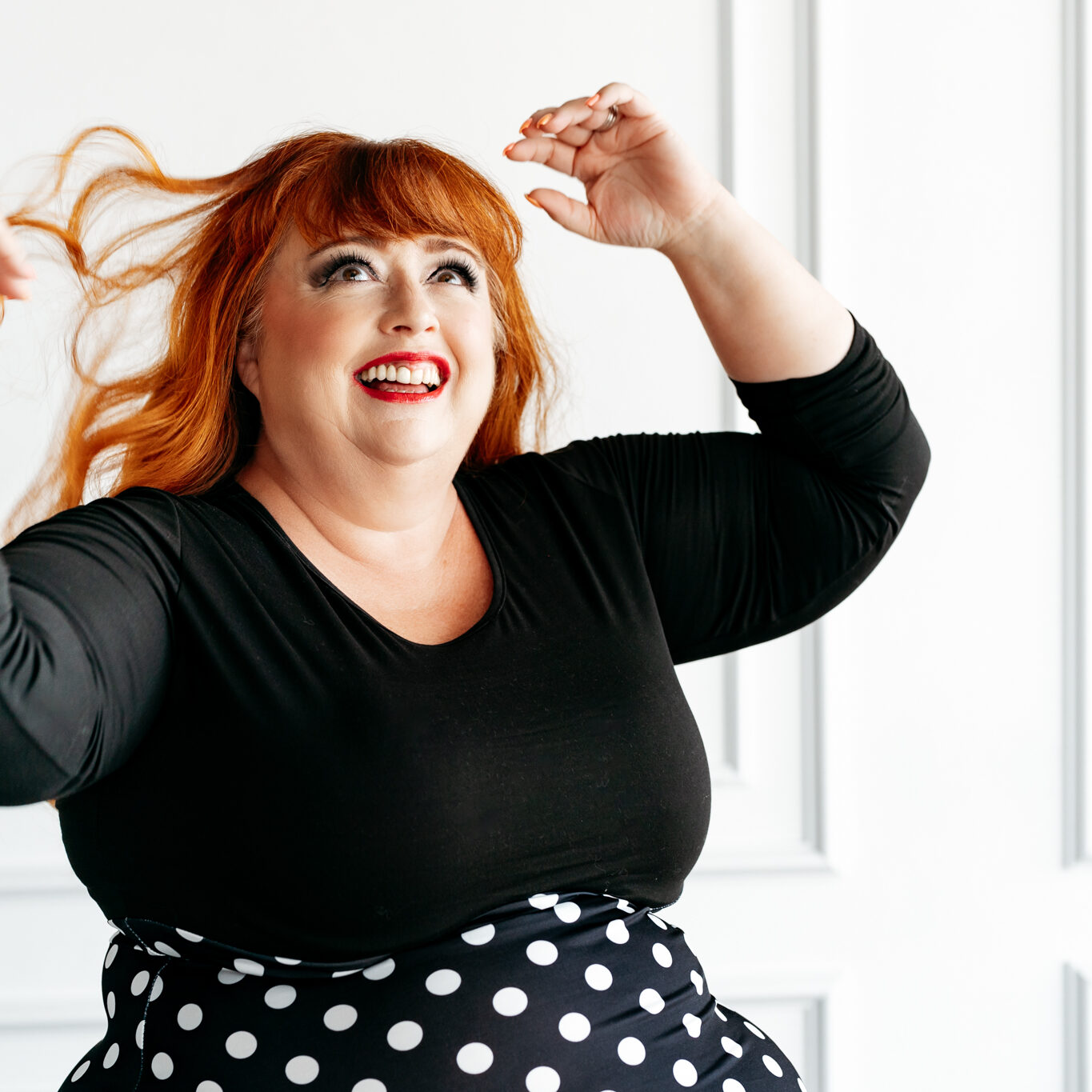 Virtual Work Wife - A person with red hair and a black top smiles while playfully automating things indoors, tossing their hair with flair. Virtual Work Wife - A person with red hair and a black top smiles while playfully automating things indoors, tossing their hair with flair.