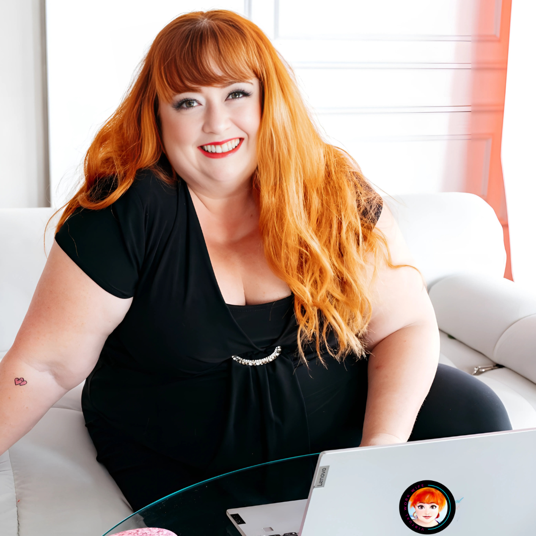 Virtual Work Wife - Michelle Bell, a noted author with long red hair, sits on a white sofa, smiling at the camera. Nearby, her laptop rests on a glass table, hinting at her next literary creation.